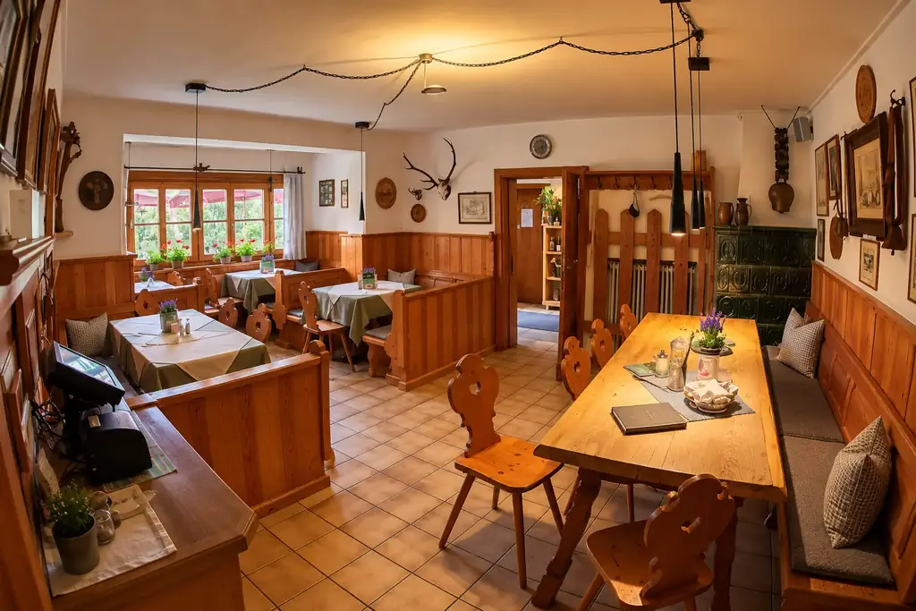 Helle Gaststube mit Holztäfelung, Eckbänken, grünem Kachelofen und Geweih an der Wand