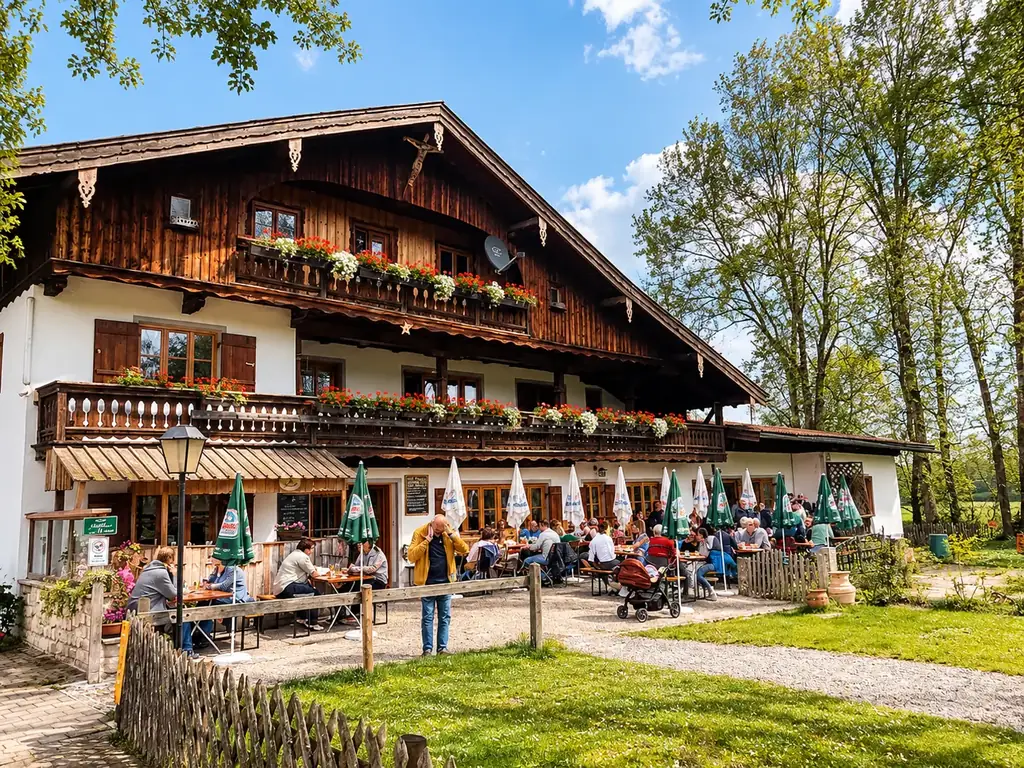 Die Moosmühle mit Blumenbalkonen und gut besuchter Terrasse unter grünen Sonnenschirmen