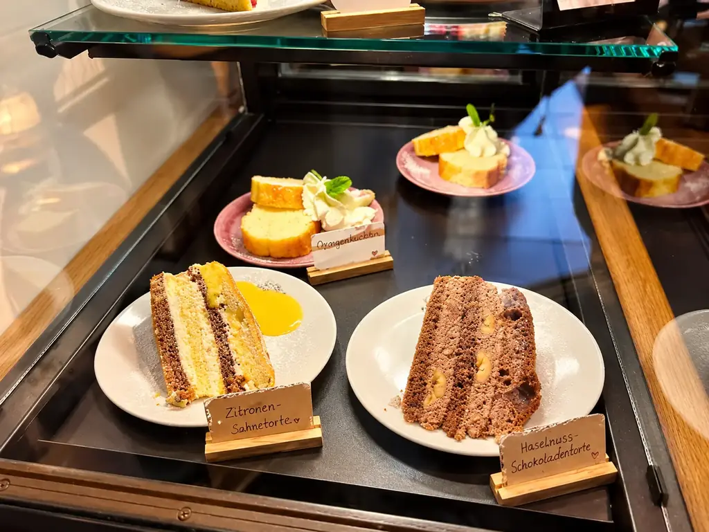 Kuchenvitrine mit Zitronen-Sahnetorte, Haselnuss-Schokoladentorte und Orangenkuchen